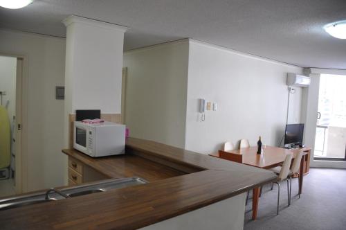 a kitchen with a counter with a microwave and a table at Accommodation Sydney City Centre - 2 Bedroom Apartment with Balcony on Top Floor in Sydney
