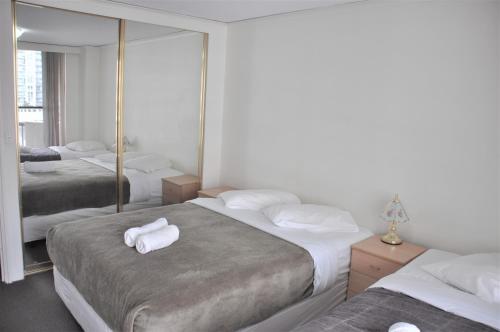 a hotel room with three beds with towels on them at Accommodation Sydney City Centre - 2 Bedroom Apartment with Balcony on Top Floor in Sydney