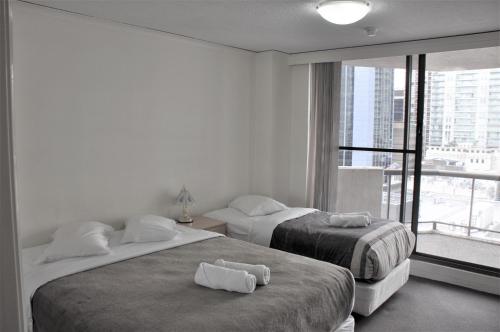 two beds in a room with a large window at Accommodation Sydney - Kent Street in Sydney