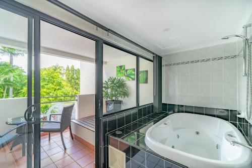 a bath tub in a bathroom with a window at Regal Port Douglas in Port Douglas