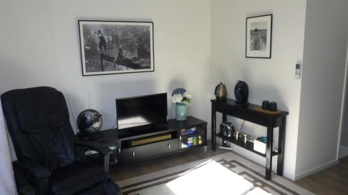 salon z krzesłem i telewizorem w obiekcie Modern Self Contained Apartment in Riverhead w mieście Riverhead