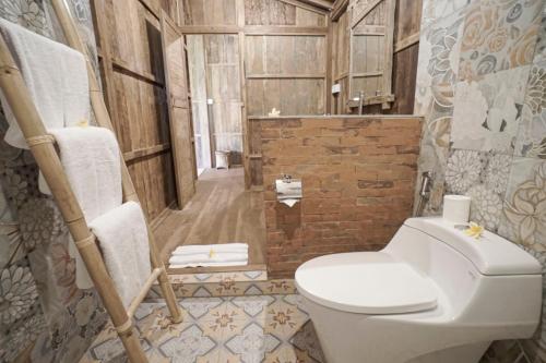 a bathroom with a toilet and a brick wall at Kirani Joglo Villa Bali by Mahaputra in Sukawati