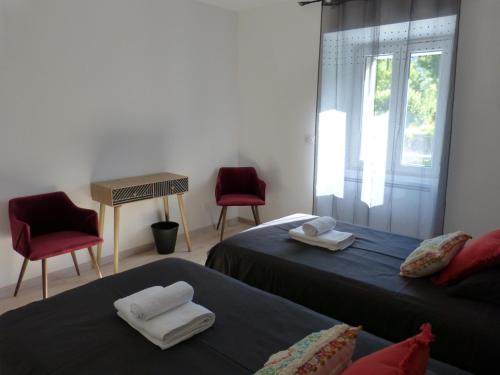 Zimmer mit 2 Betten, 2 Stühlen und einem Fenster in der Unterkunft Le Manoir, appartement Beryl in Le Bourg-dʼOisans