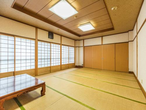 an empty room with a table and windows at Tabist Miya Yokkaichi Suizawa in Suizawa