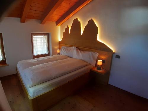 a bedroom with a bed and two lights on the wall at Appartamento 3cime Stefania in Padola