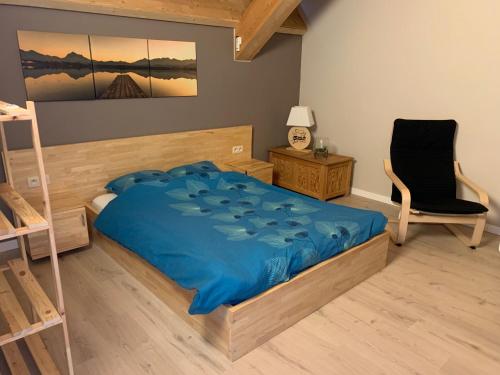 een slaapkamer met een bed met een blauw dekbed en een stoel bij Ecolodge Otra Cosa in Mouscron