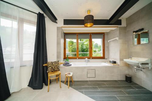 een badkamer met een bad, een wastafel en een raam bij Appartement Les Bleuets in La-Roche-en-Ardenne