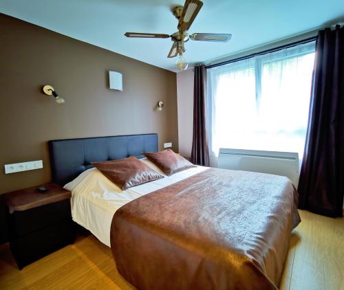 Schlafzimmer mit einem großen Bett und einem Deckenventilator in der Unterkunft Appart Hotel Relax Spa in Lens