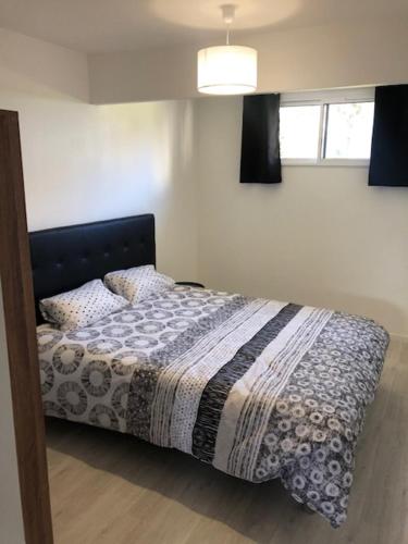 une chambre avec un lit avec une couverture et une fenêtre dans l'établissement Loft Rêve du Soir 125 m2 climatisé 350 m de la gare, à Lourdes