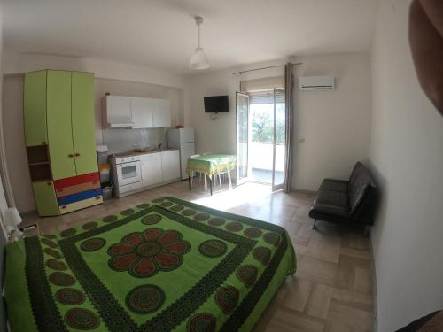 Cet appartement comprend une chambre avec un lit vert et une cuisine. dans l'établissement Rivamare Campora Casa Vacanze, à Campora San Giovanni