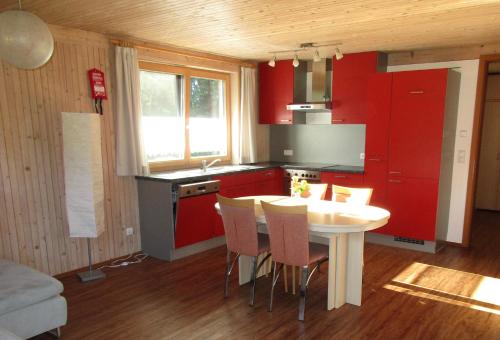 a kitchen with red cabinets and a white table and chairs at Naturparadies Silvia in Alberschwende