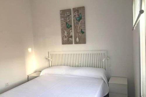 una camera con un letto bianco con due immagini sul muro di Apartamento La Playa a Nerja