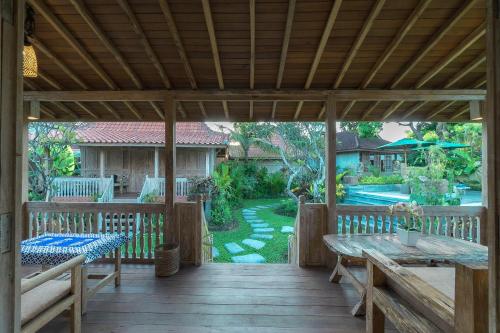 a wooden deck with a table and benches on it at Kirani Joglo Villa Bali by Mahaputra in Sukawati