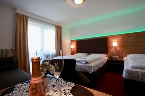 a hotel room with two beds and a bottle of wine at Hotel-Restaurant am Hochfuchs in Eugendorf