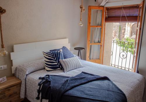 a bedroom with a bed with blue pillows and a window at Cal Tomaset in Prades