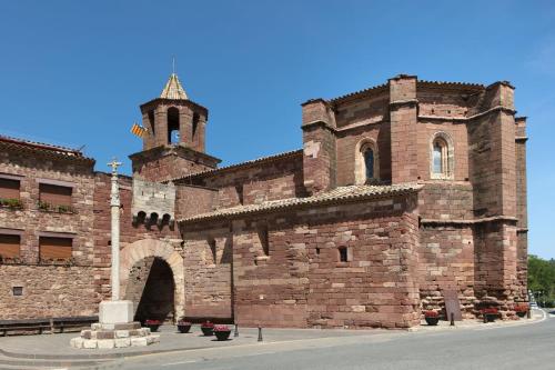 a large brick building with a tower and a church at Cal Tomaset in Prades