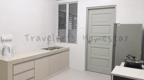 a white kitchen with a sink and a door at Traveler's homestay 旅人窝@ The Venus Sitiawan in Kampong Lumut Kiri