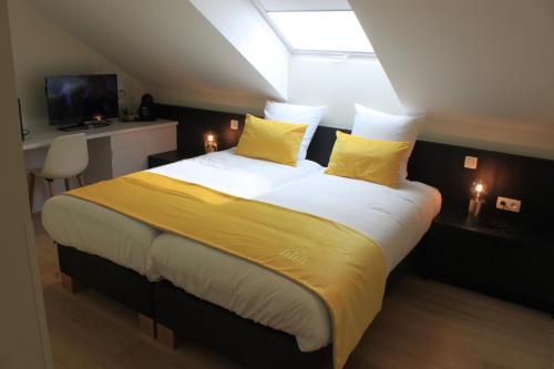 a bedroom with a large bed with yellow pillows at B&B Atuatuca in Tongeren