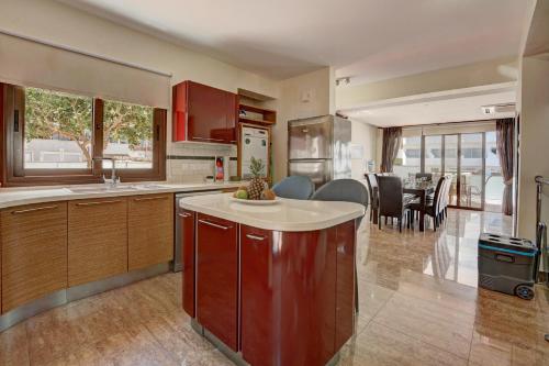 a kitchen with red cabinets and a dining room at Seafront Protaras Villas in Protaras