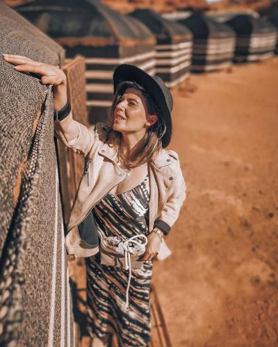 a woman wearing a hat standing next to a fence at golden day in Wadi Rum
