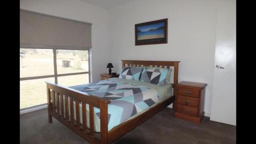 a bedroom with a wooden bed and a window at Gone skiing in Bonnie Doon