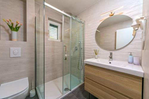 a bathroom with a shower and a sink and a mirror at Apartman Macan in Brela