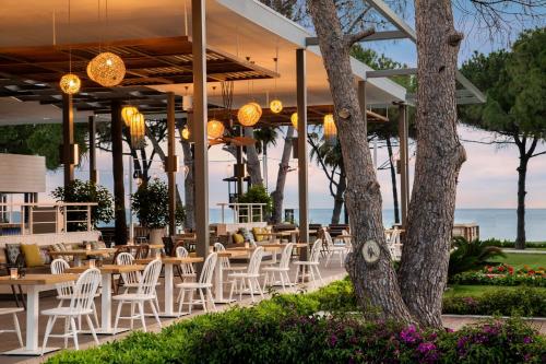 a restaurant with white chairs and tables and a tree at Acanthus Cennet Barut Collection - Ultra All Inclusive in Side