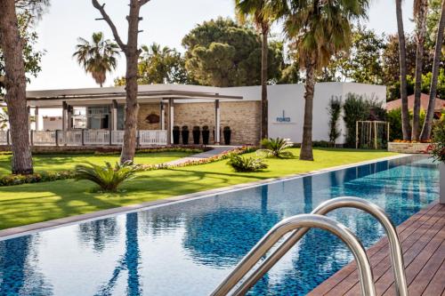 a swimming pool in front of a house with palm trees at Acanthus Cennet Barut Collection - Ultra All Inclusive in Side