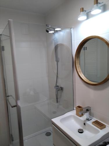 ein Bad mit einer Dusche, einem Waschbecken und einem Spiegel in der Unterkunft Nowy Apartament Bałtycka 11 in Kołobrzeg