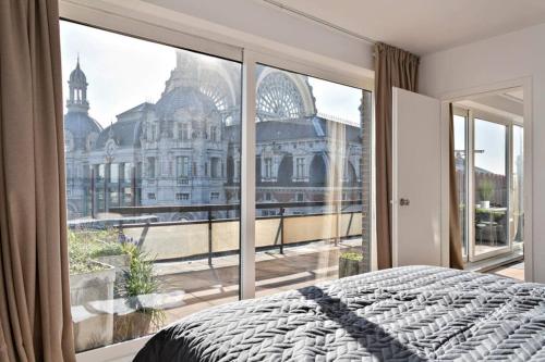 una camera da letto con una grande finestra con vista su un edificio di City PENTHOUSE, rooftop terrace, free NETFLIX, wifi and airco ad Anversa