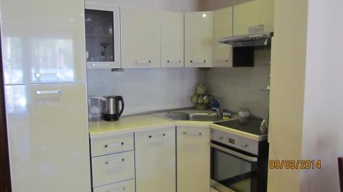 a small kitchen with white cabinets and a sink at jaren in Łukęcin