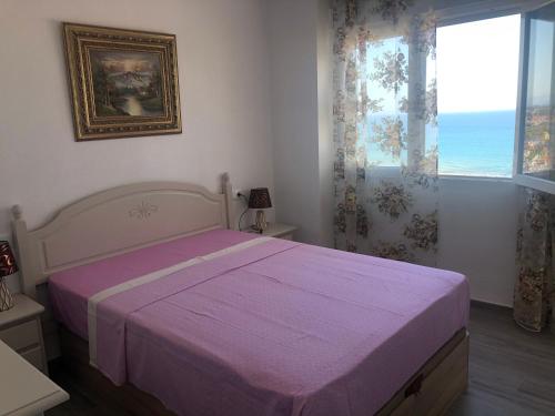 ein Schlafzimmer mit einem großen Bett mit einer lila Decke in der Unterkunft Guadalajara apartamento in Torrevieja