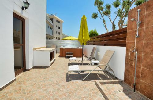 a patio with two chairs and a yellow umbrella at Seafront Protaras Villas in Protaras