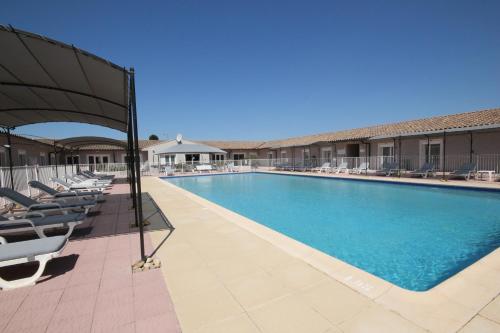 une grande piscine avec chaises longues et parasols dans l'établissement Hôtel Saint Louis, au Thor