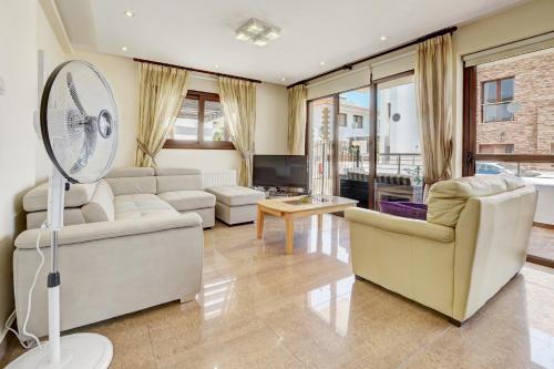 a living room with white furniture and a fan at Seafront Protaras Villas in Protaras