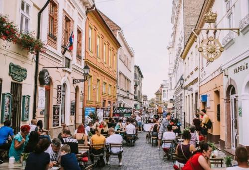 a group of people sitting at tables in a street at Malasits Apartman in Győr