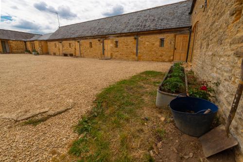 a building with a bunch of plants in a courtyard at Mill Cottage - Ash Farm Cotswolds in Stow on the Wold