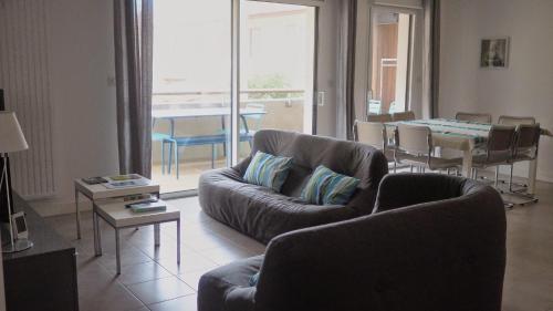 un salon avec des canapés et une table ainsi qu'une salle à manger dans l'établissement magnifique appartement Capbreton, à Capbreton