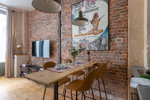 une salle à manger avec un mur en briques et une table et des chaises en bois dans l'établissement Boutik Boheme Le Loft Batignolles, à Paris
