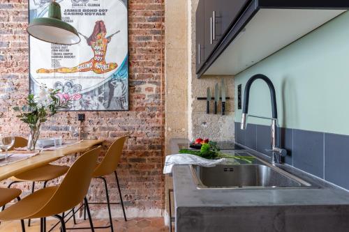 una cucina con lavandino e muro di mattoni di Boutik Boheme Le Loft Batignolles a Parigi