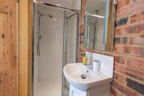 a bathroom with a sink and a brick wall at Mill Cottage - Ash Farm Cotswolds in Stow on the Wold