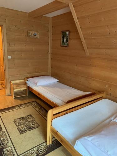 a room with two beds in a log cabin at Pokoje u Magdusi przy termach in Witów