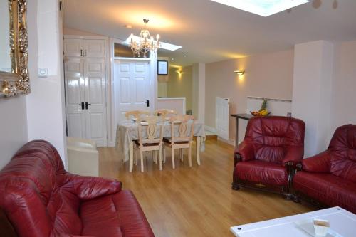 een woonkamer met een rode bank en een tafel en stoelen bij Cleomack View, Annex apartment with Hot Tub in Hilltown