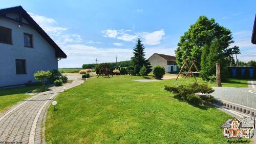 a large yard with a playground and a house at Agrosielanka in Lipnica