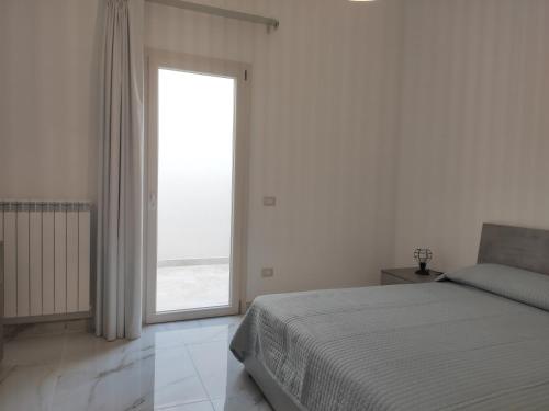 um quarto com uma cama e uma grande janela em Casa Vacanze Vega em Porto Cesareo