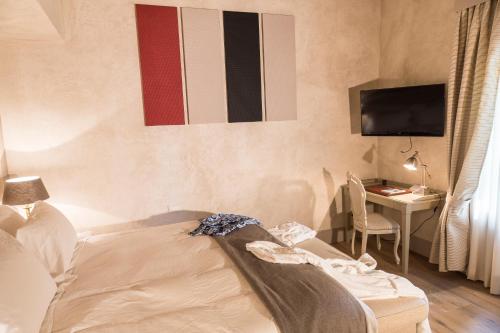 a room with a bed and a desk and a television at La Barchessa di Villa Pisani in Lonigo