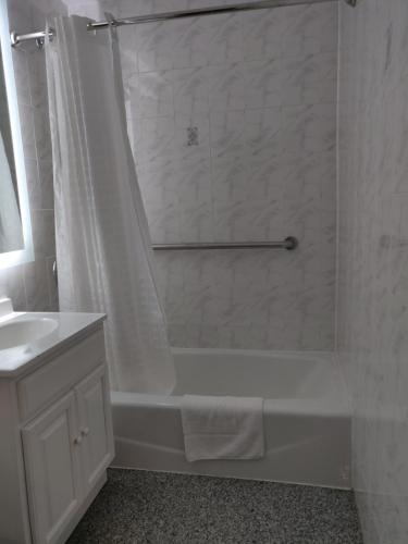 a white bath tub sitting next to a white sink at Hotel Key in Queens