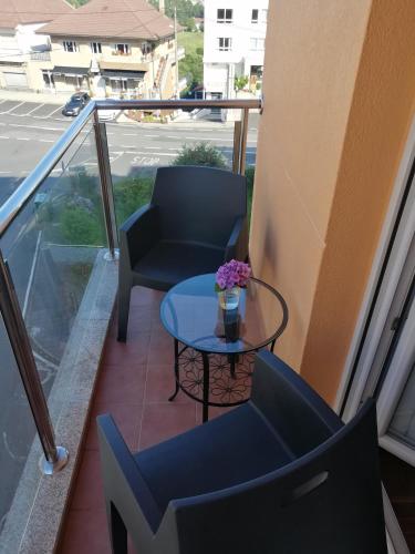 a balcony with two chairs and a table with flowers on it at Apartamentos MonteBlanco Costa da Morte in Neaño