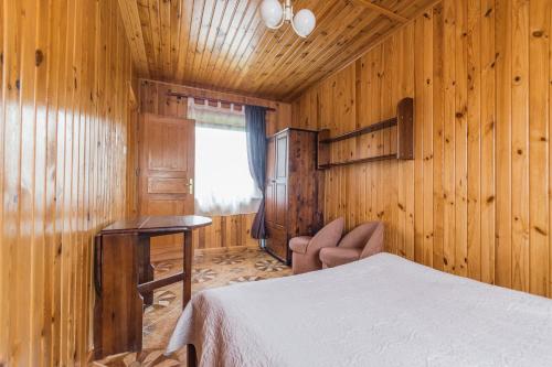 Schlafzimmer mit Holzwänden, einem Bett und einem Fenster in der Unterkunft Stanica Przygody in Sztutowo