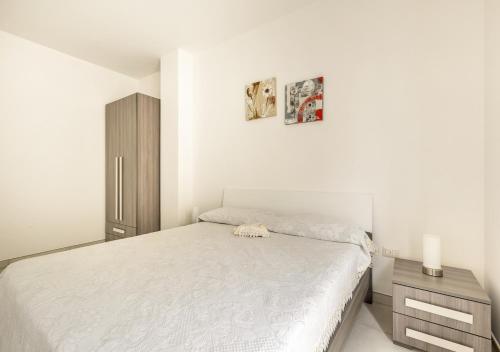 a white bedroom with a bed and a night stand at Villetta Verdi a Pescoluse in Marina di Pescoluse